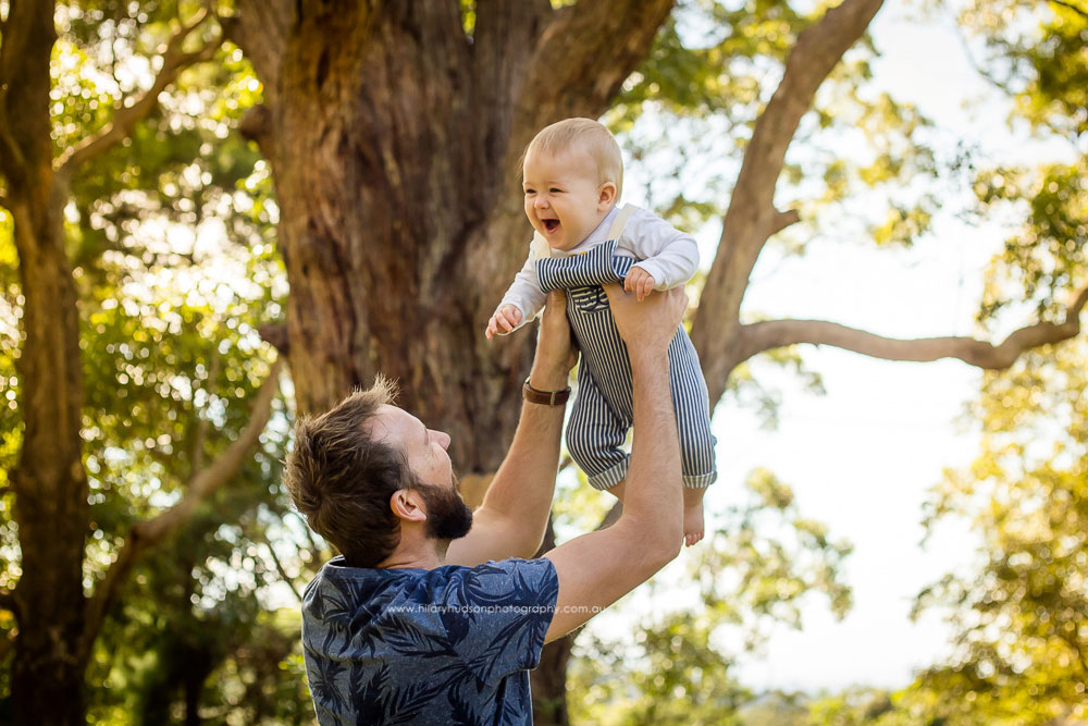 Dad lifts his baby up into the air, baby is laughing with delight!